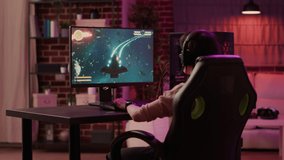 Over shoulder view of gamer girl relaxing and streaming on internet fast paced space shooter simulation gameplay while talking using headset. Woman playing rpg action game on professional pc setup.