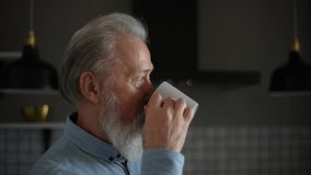Close-up face of pensive bearded senior older man with grey hair drinking tea at home having calmness emotion. Lonely mature male drinking coffee in morning looking out window in kitchen. - Powered by Shutterstock - Get 15% off with code: PIKWIZARD15