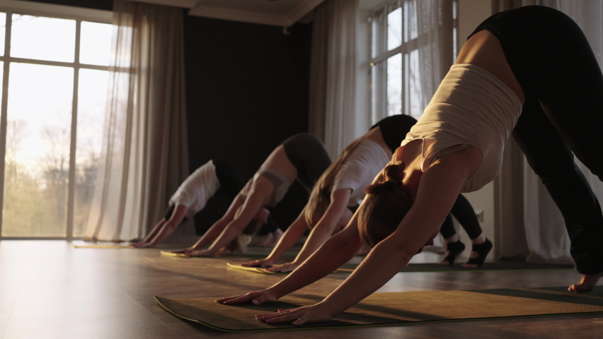 A group of women of different ages, fat and thin, practice yoga together with an instructor at sunset in slow motion. Royalty-Free Stock Footage #1090830059