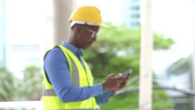 Slow motion of a black foreman  in reflective suit using mobile phone. Focusing from blur to clear, Engineering and technology concept.