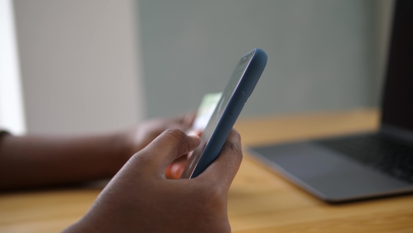 Close-up of a young African American woman hand holding a mobile phone, scrolling through a personal page on a social network, looking through photos, reading news in the media, using a dating app Royalty-Free Stock Footage #1090837827