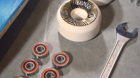LA, UNITED STATES, APRIL 2022: CLOSE UP: Detailed overview of lined up skateboard wheels and bearings on gray countertop. Moving shot of arranged skateboard elements and other parts ready for assembly