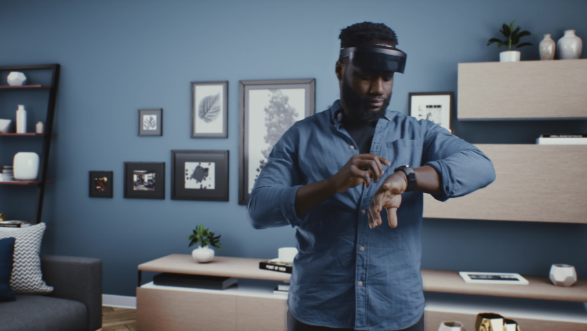 African American man in VR glasses in the cyberspace of the metaverse at a business meeting, discussing artificial intelligence depicted as a hologram with avatars of colleagues. Royalty-Free Stock Footage #1090841879