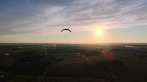 a paraglider flies at sunset over the plains