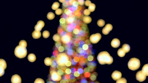 Large New Year's Christmas tree decorated with luminous multi-colored garlands and illumination at night. Christmas tree with flashing lights. Blurred background. New Year and Christmas holidays