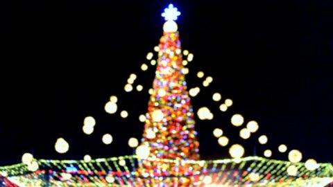 Large New Year's Christmas tree decorated with luminous multi-colored garlands and illumination at night. Christmas tree with flashing lights. Blurred background. New Year and Christmas holidays
