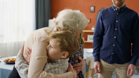 Joyous elderly grandmother giving hugs to little grandkids while greeting family at home for holiday dinner - Powered by Shutterstock - Get 15% off with code: PIKWIZARD15