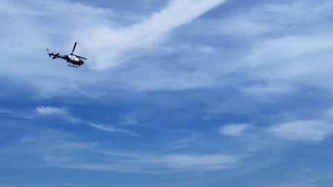A police helicopter flies over the city against the blue sky