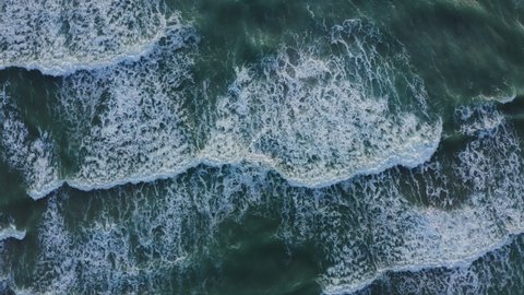 Drone shot showing waves rolling onto a beach. Aerial View Of of Clear turquoise sea and tropical beach.  Beautiful sea waves Water texture Top view,  Summer sunset seascape beautiful beach