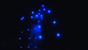Bright colored lights blink and move in the hazy dark night sky. Drone show