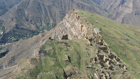 Drone flying over ancient stone watchtowers and edge of high mountain cliff in village of Goor, Dagestan