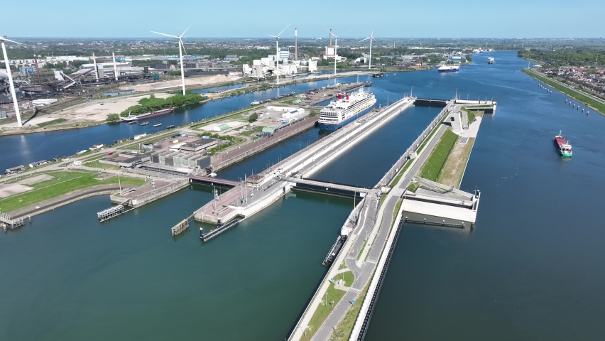 4k aerial video of cruise ship leaving large sea sluice towards Amsterdam in the Netherlands. Tata steel factory in the back ground