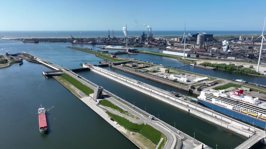 4k aerial video of cruise ship leaving large sea sluice towards Amsterdam in the Netherlands. Tata steel factory in the back ground