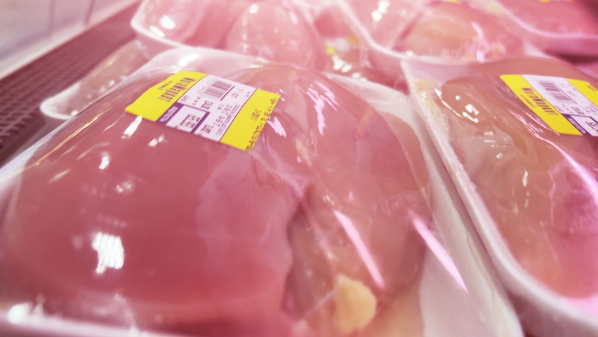 Raw chicken and turkey fillet in plastic containers wrapped in cling film are on the shelves of the refrigerator in the supermarket. Closeup Royalty-Free Stock Footage #1090880835