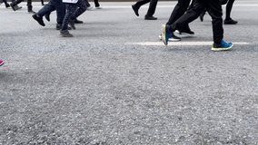 A group of marathon runners, a race in the city. Bottom view of the legs of the runners. Slow-motion video of people running on the main street of the city.