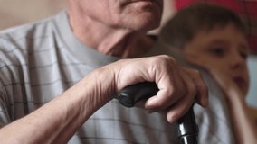 Caucasian grandson 7-8 years old hugging his grandfather sitting with a walking stick at home. Pensioner and grandson, family communication, caring for the elderly.Selective focus. Family ties - Powered by Shutterstock - Get 15% off with code: PIKWIZARD15