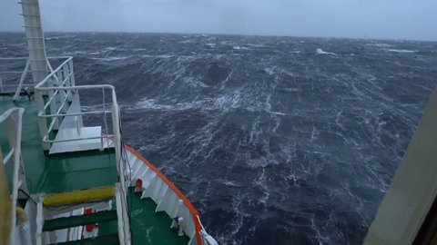 Storm. Sea. Vessel. View from bridge. Bow breaks waves. A lot of splashes. Water completely splashed window. Strong pitching. High waves hit ship. White foam on water.