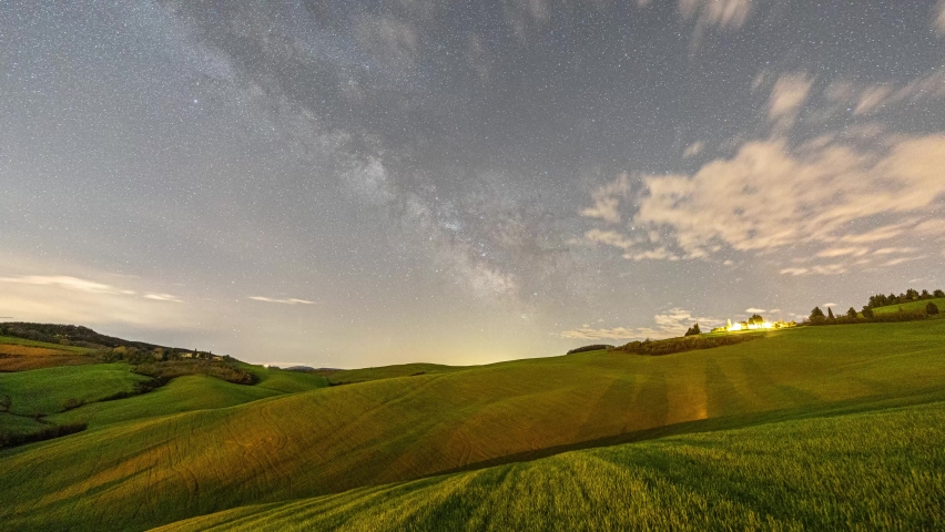 4k time lapse of milky way galactic core moving across the sky over the rolling green hills of Tuscany, Italy