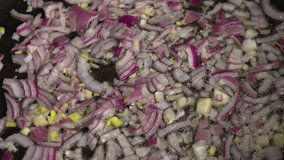 Video of mixing and cooking freshly chopped red spanish onion in frying pan with oil with wooden spatula