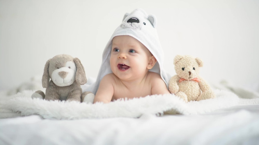 Cute funny little baby boy with toys, relaxing in bed after bath, laughing happilyy boy with toys, relaxing in bed after bath, laughing happily. High quality 4k footage Royalty-Free Stock Footage #1090892057
