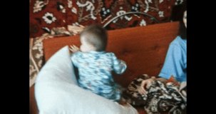 Funny little child is playing in home room. Happy smiling baby girl in dress runs in Soviet apartment interior. Family life indoors. Vintage color film. Sentimental family archive. Retro 1980s. 4k
