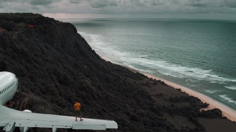 Man walks on plane wing overlooking cliff in Bali, Indonesia 4K