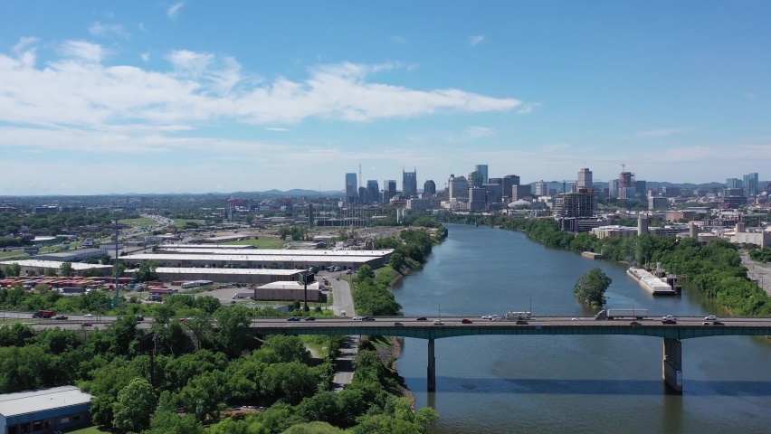 Aerial Nashville skyline shot from north of the city on a sunny summer day. Dolly left-to-right near bridge going over Cumberland River into city of Nashville. 