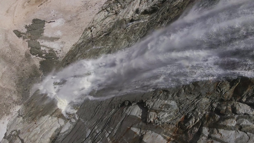 A beautiful waterfall in the upper reaches of the Tanadon Gorge. Hanging glacier Tanantseti from under which flows a stormy water stream. Caucasus. Digoria, North Ossetia-Alania, Russia. Drone view