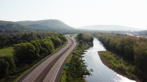 Oneonta, New York, USA - 05-23-2002: Interstate 88 runs through Oneonta next to the Susquehanna River with a cell phone tower in the distance.  Drone pull back.