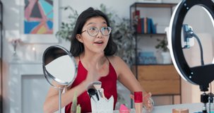 Young Asian female influencer beauty blogger recording video. Demonstrates her product,foundation,makeup sponge in front of phone camera,social media.