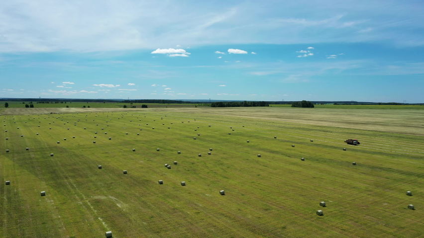 Aerial view of hayfield. Beautiful dynamic landscape with hay bales. Haystacks lay upon agricultural field taken on drone. Agriculture concept. | Shutterstock HD Video #1090922053