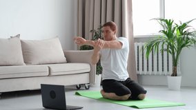 Self-care during stay at home. Fitness training, stretching exercises online men at home with laptop. guy lying on fitness mat online yoga lessons blank laptop screen.