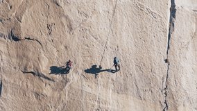 Rock climbing footage shot on RED camera in Yosemite National Park on Sunny Summer day. Two alpinists helping each other with rope and mountain climbing professional tools. Extreme sport concept video