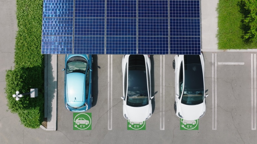 Aerial view of a car parking under solar panels. 4K electric, zero pollution, green energy concept cars at modern city parking lot. Alternative energy for ecological cars under blue solar batteries Royalty-Free Stock Footage #1090932495