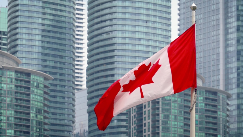 Canada national flag is waving in wind against modern building. Flag of Canada on flagpole is flapping in wind. Canadian flag fluttering, background building glass windows. Fabric Canadian flag waving Royalty-Free Stock Footage #1090941045