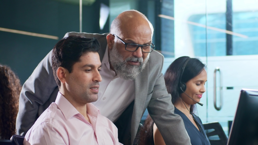 Modern Indian Asian attractive smiling customer support care male or man employee busy working together on a computer while interacting or talking to old senior boss. Business, unity Finance concept Royalty-Free Stock Footage #1090942933