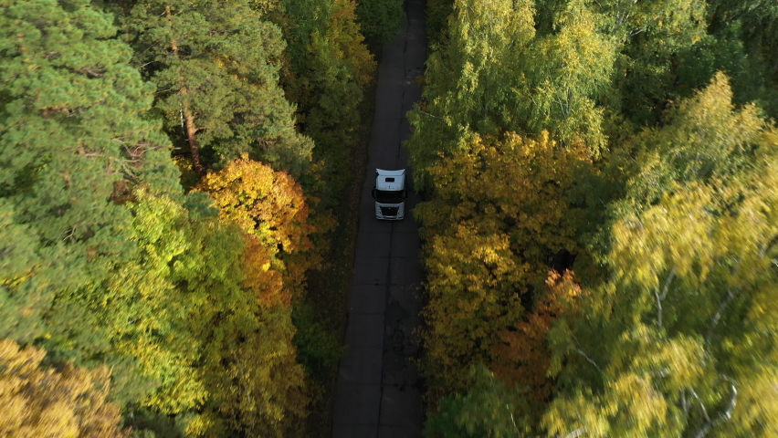 One Semi Truck without trailer traveling alone on dense flat forest asphalt straight empty road. Amazing aerial perspective of truck among the woods. Tall pine trees in forest. Autumn trees. | Shutterstock HD Video #1090943071
