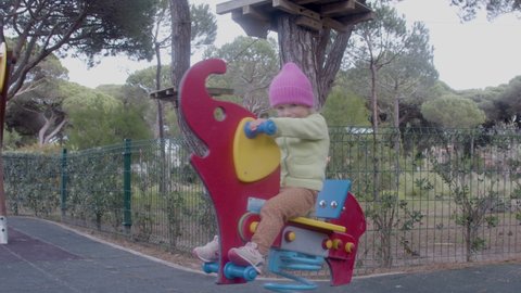 Excited little girl swinging on rocking toy on playground. Happy child riding rocking elephant, having fun, smiling, spending time outdoor. Joy, recreation, childhood concept