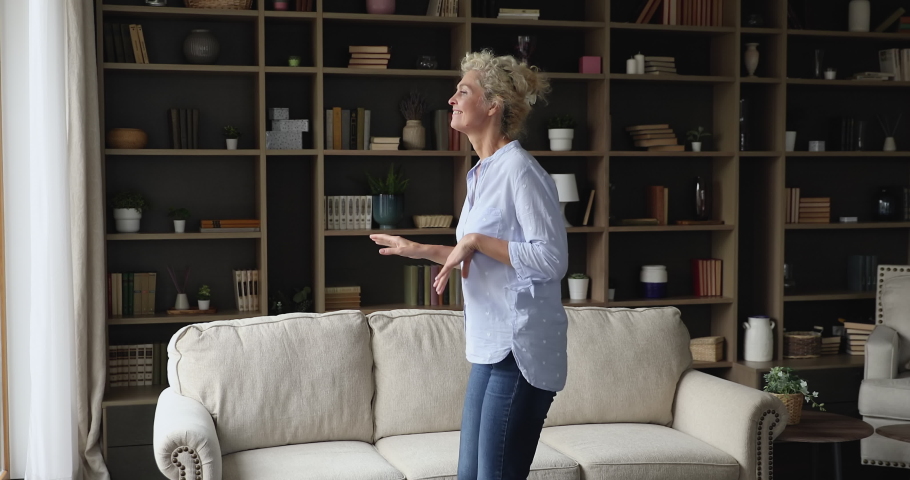 Funny lively older woman dance alone in cozy living room. Senior female listen favourite track moving to music looking carefree enjoy untroubled retired life at own modern home. Leisure, hobby concept Royalty-Free Stock Footage #1090949429