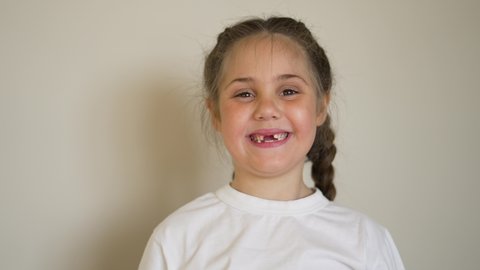 Happy child smiles with his teeth at camera. Cute little girl in bright room alone with beautiful toothless smile. child is losing teeth. Happy child smile at the camera.