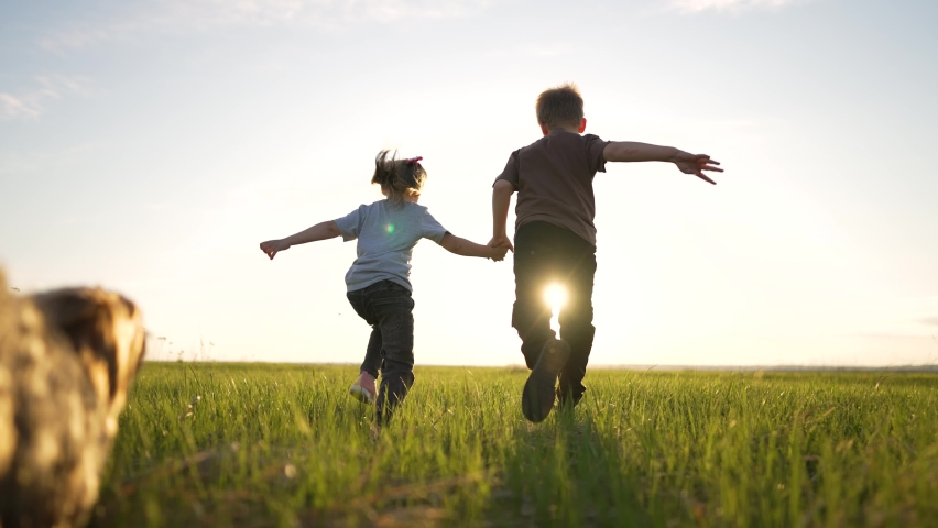 Happy cheerful family. Children have fun running on green grass in park with dog. Girl and boy are play in field in the spring with dog. Love for pet. Children run with dog at sunset in summer. | Shutterstock HD Video #1090954593