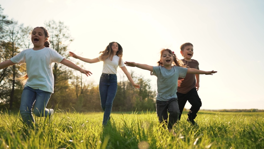 Schoolchildren play in spring vacation park. Active happy group of children run on grass in field in summer. Family outdoors in sun. Child on playground.Happy family concept.School holidays in garden Royalty-Free Stock Footage #1090954603