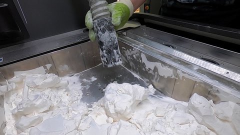 Man cleans details printed on industrial 3D printer from white plastic powder. Automated additive technologies. Person cleans vacuum cleaner plastic powder from models printed on 3D printer. Top view