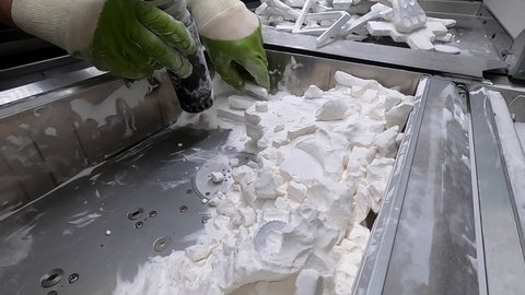 Man cleans details printed on industrial 3D printer from white plastic powder. Automated additive technologies. Person cleans vacuum cleaner plastic powder from models printed on 3D printer. Top view