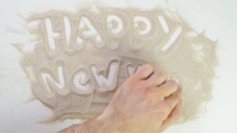 happy new year. Top view draw on the sand. Caucasian hands write text in beige sand. Vacation and travel. Beach on vacation. Sand painting. Creativity from natural materials.