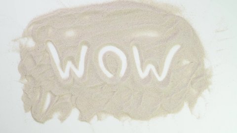 wow text. Top view draw on the sand. Caucasian hands write text in beige sand. Vacation and travel. Beach on vacation. Sand painting. Creativity from natural materials.