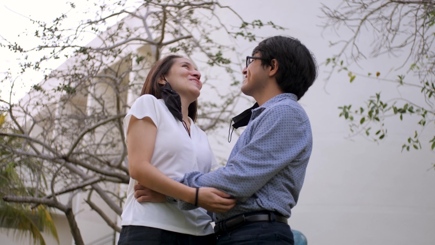 Latin American Married Couple without face masks chatting, laughing and kissing in an outdoor park at dusk in times of pandemic COVID-19. Slowmotion Romantic Scene Of Mexican Couple