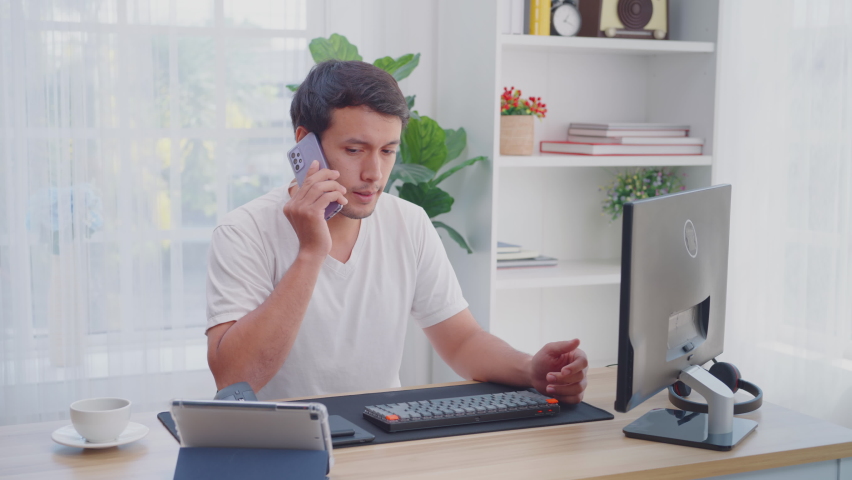 Tired male working at home using a computer, talking on the phone, and using his hand to close his eyes looking Anxious. Man ethnicities caucasian, 29 Years | Shutterstock HD Video #1090966213