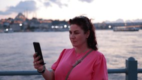 A young brunette woman uses a smartphone, talks, takes pictures and shoots video