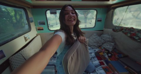 Cinematic authentic pov shot of carefree couple in love having fun to fight with pillows inside their trailer while enjoying together romantic trip with camping caravan.